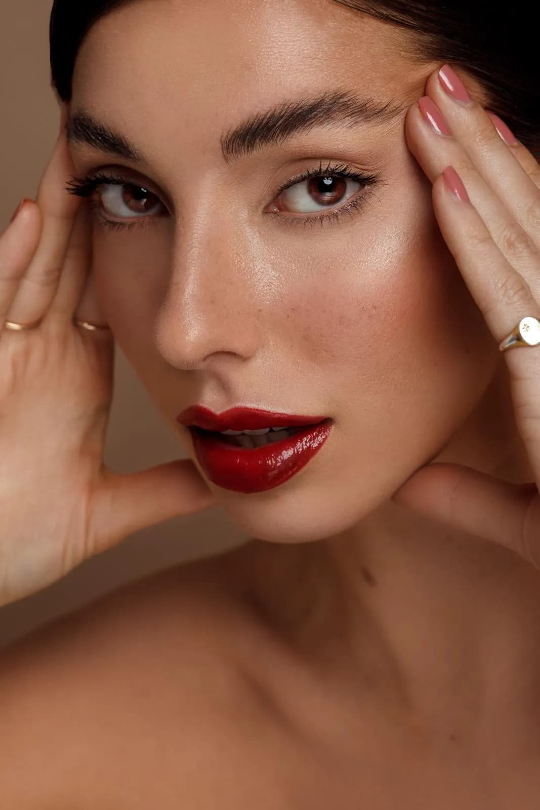 Close-up van een model met rode lippen, handen langs het gezicht